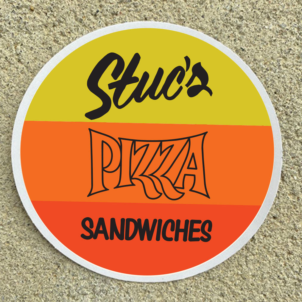 Round sign with 'Stuc's Pizza Sandwiches' text on a textured surface